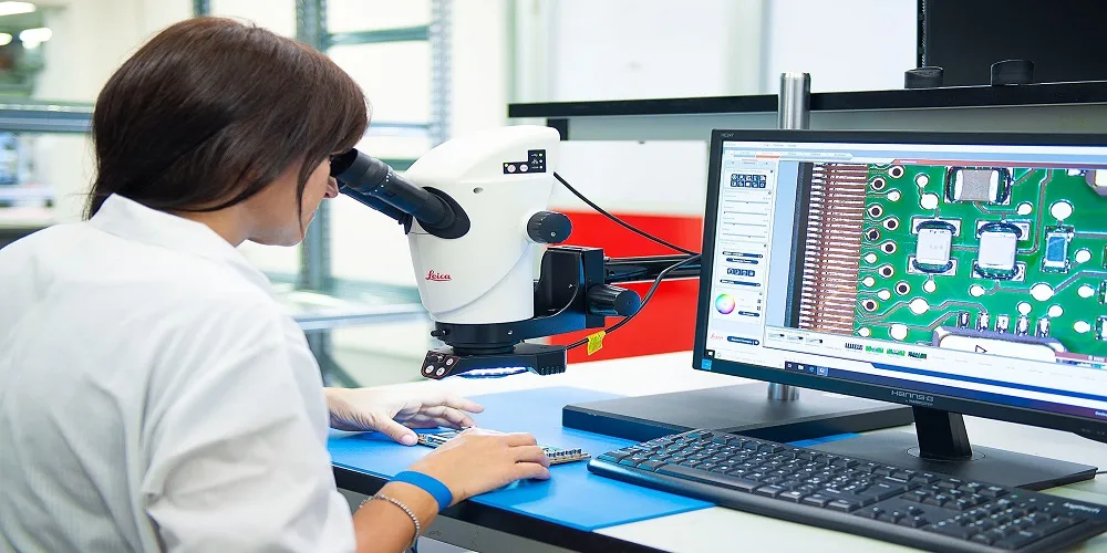 Technician inspecting a circuit board under a microscope
